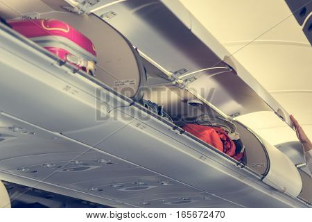 Airplane interior with overhead luggage compartment. doors opened before take-off.