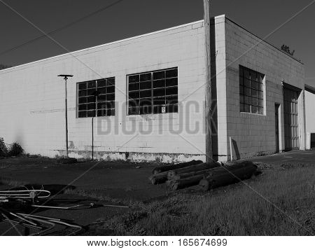 An old abandoned concrete block building with multiple window panes and electrical equipment stacked outside on a sunny spring day in the little town of Oakridge in Lane County in Western Oregon.