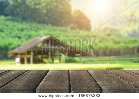 Wood plank on natural green grass field & sky background with farmer cottage- can use for display or montage your products