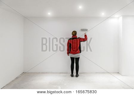 Female Painter With Paint Roller In Front Of Wall As Template