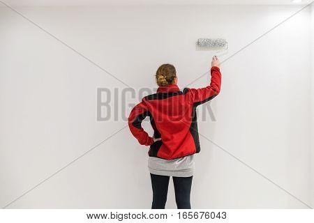 Female Painter With Paint Roller In Front Of Wall As Template