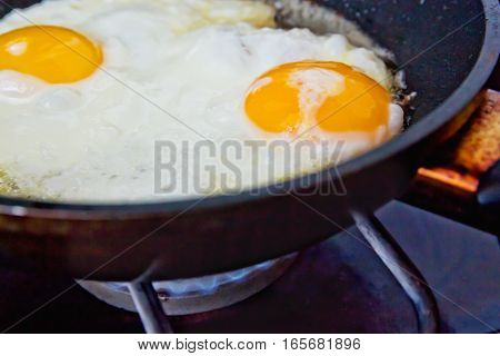 Fried eggs in a frying pan on a gas burner