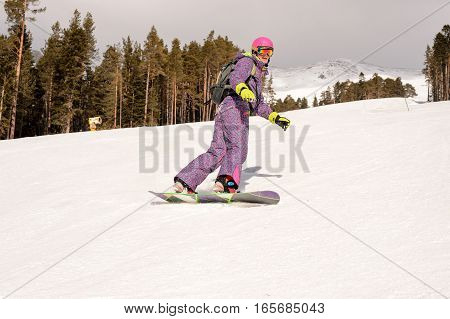Beautiful beginner snowboarder girl in caucasian mountains