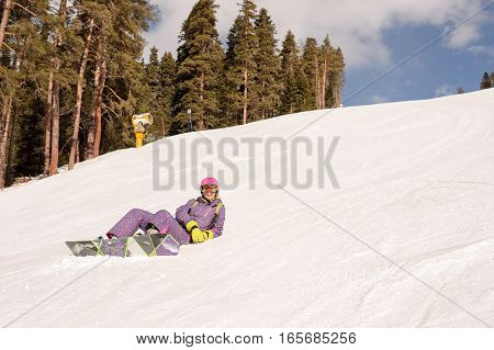 Beautiful beginner snowboarder girl in caucasian mountains