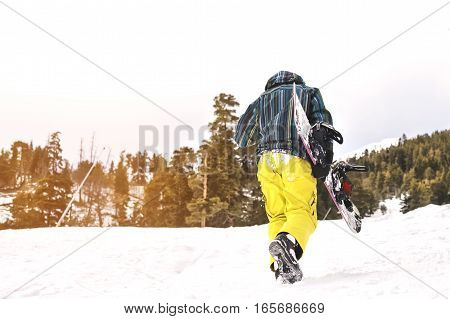 snowboarder walking against snowy mountains and blue sky