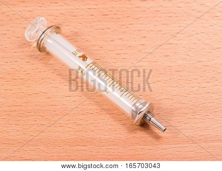 glass insulin syringe on a wooden background on the division syringe for definition of a dose