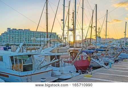 The bright sunset sky behind the masts of yachts in port of Eilat Israel.