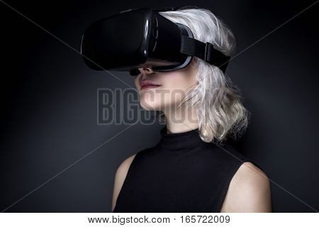 Woman wearing a futuristic looking virtual reality headset goggles. The device is technology that lets video gamers experience VR or AR augmented reality