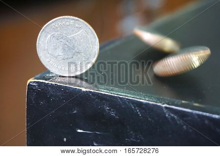 The Thai baht currency coin on the table in a vertical position with a moving coin.