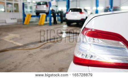 Automobile service - mechanics checking lifted car, defocused background, slider