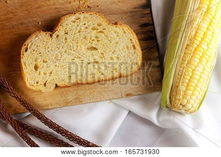bread made from corn on the white fabric. Slices of corn bread laying on a chopping Board and Sweet corn cobs
