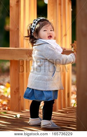 Baby girl standing on the wood bench