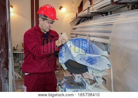 Worker at Workshop Operating Circular Saw.
PVC window and door manufacturing. Cutting window frame profile.