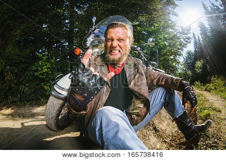 Male Biker Sitting On Dirt Road Near Motorcycle