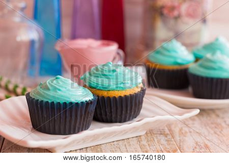 Two vanilla cupcakes with mint cream on a decorative plate