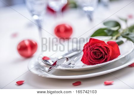 Table setting for valentines or wedding day with red roses. Romantic table setting for two with roses plates cups and cutlery.