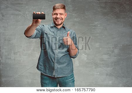 The young smiling caucasian businessman on gray studio background with mobile phone