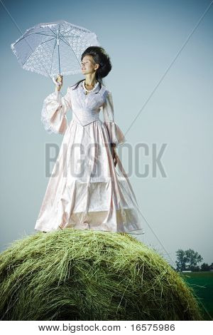 Piękna kobieta w sukienka vintage, stojąc na stogu siana