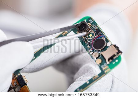 Close-up Of A Technician Hand Fixing Mobile Phone Camera
