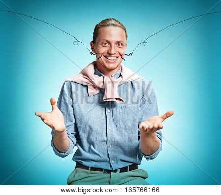 Happy excite young man in blue shirt smiling and celebrating his succcess over blue studio background