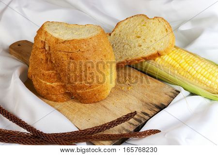 bread made from corn on the white fabric. Slices of corn bread laying on a chopping Board and Sweet corn cobs