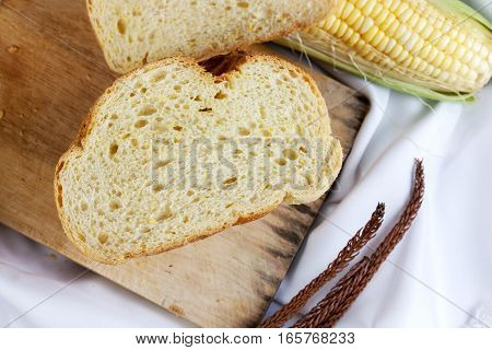 bread made from corn on the white fabric. Slices of corn bread laying on a chopping Board and Sweet corn cobs