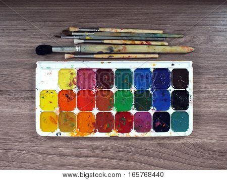 Watercolor paints and brushes on a wooden table