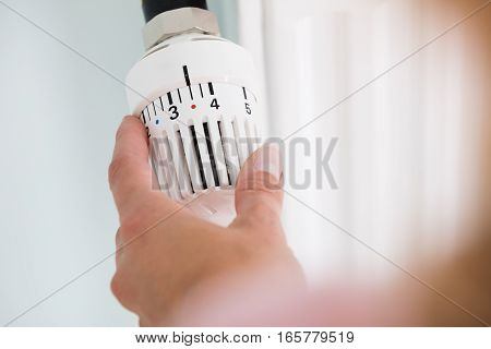 Close-up Of Person Hands Adjusting Thermostat Radiator Valve
