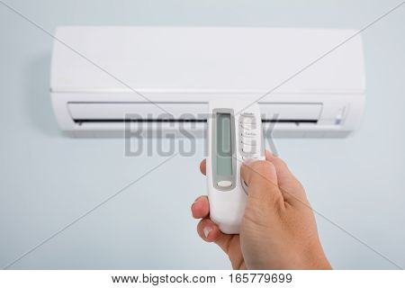 Close-up Of A Person Hand Operating Air Conditioner With Remote Control At Home