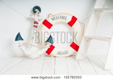 Anchor and life buoy on a white wooden floor.