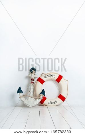 Anchor and life buoy on a white wooden floor.
