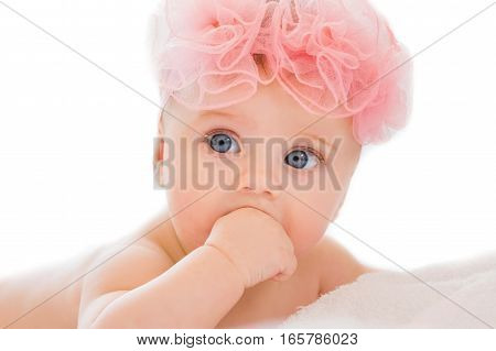 Cute little baby girl with big blue eyes wearing a pink bow.