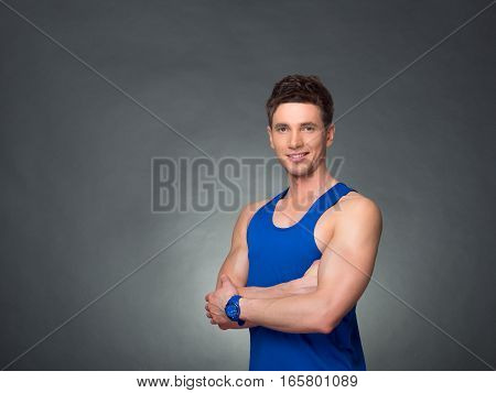 Handsome man with arms crossed looking his left on black background, blue t-shirt