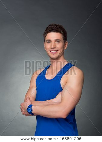 Handsome man with arms crossed looking his left on black background, blue t-shirt