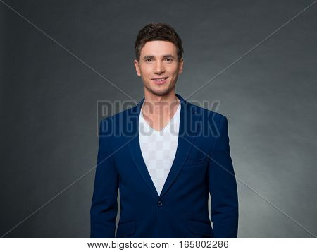 portrait of a young man on a gray background in a blue jacket