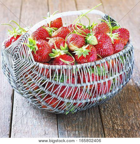 Ripe and tasty strawberries metal a basket on a wooden background