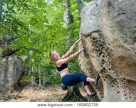 Young Woman Climbing On Large Boulders Outdoor
