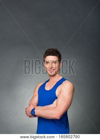 Handsome man with arms crossed looking his left on black background, blue t-shirt