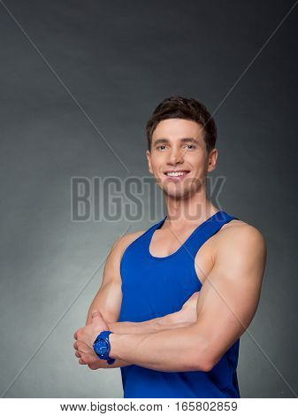 Handsome man with arms crossed looking his left on black background, blue t-shirt
