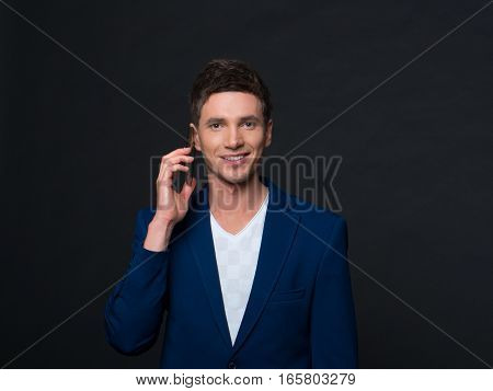 Young businessman talking on cell phone over grey background