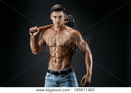 Muscular man with naked torso holding big hummer. Isolated on dark grey background