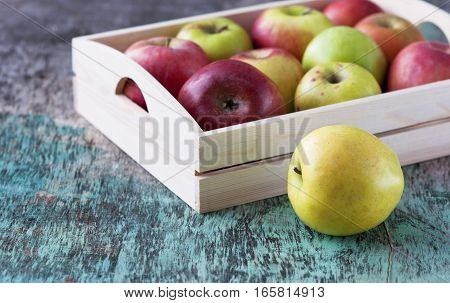 Fresh apples in a tray on a wooden background. Apples are red, green, yellow. Healthy Eating Vitamins Vegetarian Seasonal harvest.