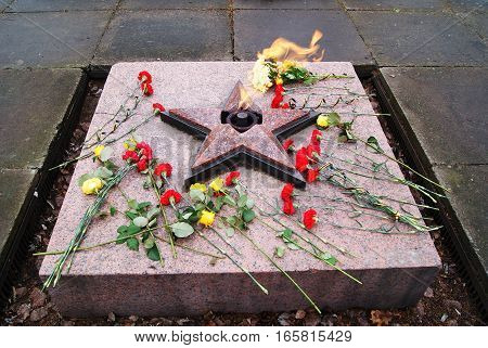 an eternal flame, red banners, veterans, spring flowers, a memorial to the fallen