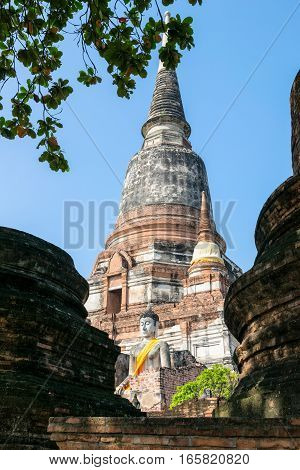 Buddha statue at the bottom of a large ancient pagoda on blue sky background at Wat Yai Chai Mongkon temple in Phra Nakhon Si Ayutthaya Historical Park Ayutthaya Province Thailand