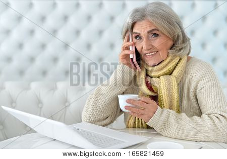 mature woman using laptop , talking on phone