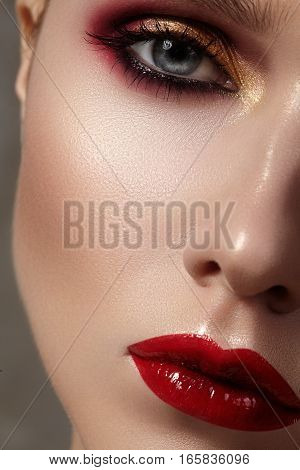 Beautiful model with fashion make-up. Close-up portrait sexy woman with glamour lip gloss makeup and bright eye shadows. Macro shot of celebrate visage clean skin lips with red lipstick eyeshadows.