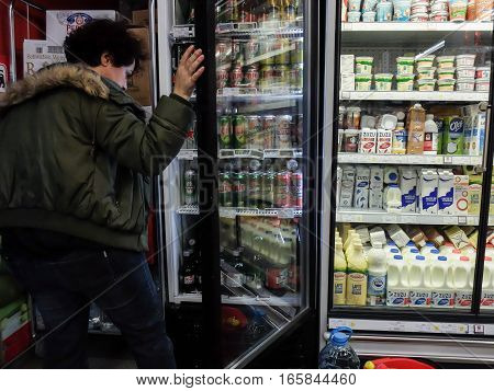 Bucharest Romania December 24 2015: A woman chooses beer from a freezer inside a supermarket in Bucharest.