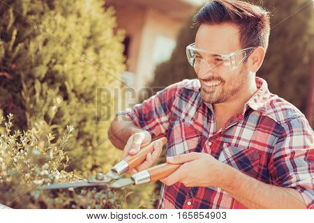 Hedge trimmingworks in a garden.Young gardener with a professional garden tools at work.