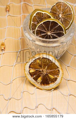 Dry lemons and limes in the glass jar on the white net and wooden board