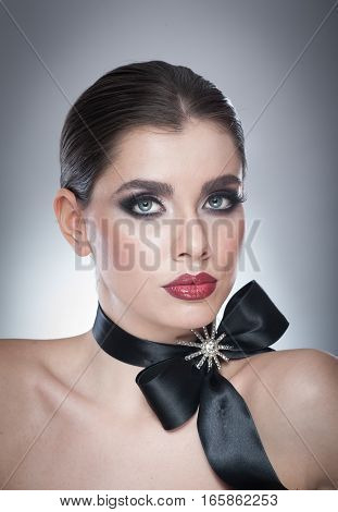 Hairstyle and Make up - beautiful female art portrait with black ribbon. Elegance. Genuine Natural brunette with ribbon - studio shot. Portrait of a attractive woman with beautiful eyes and red lips